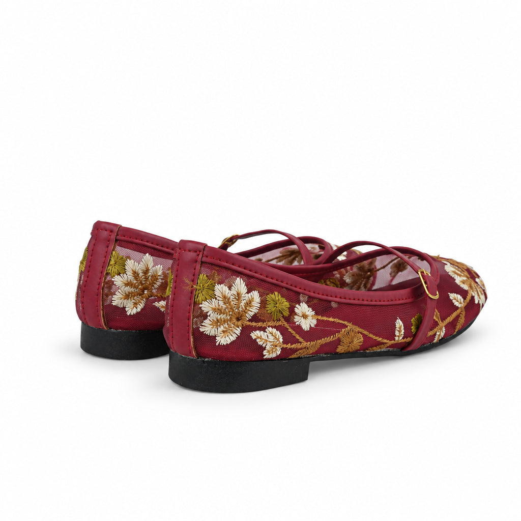 A pair of red flat shoes with white and gold floral embroidery, shown from a side-rear angle against a white studio background.