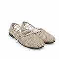 A pair of women's flat shoes with a beige woven mesh upper and thin matching straps, accented with small gold studs and a low black sole, set against a light gray background.