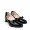 A pair of women's dark burgundy patent leather pumps with a low block heel and a small black ribbon bow on the toe, shown on a white studio floor.