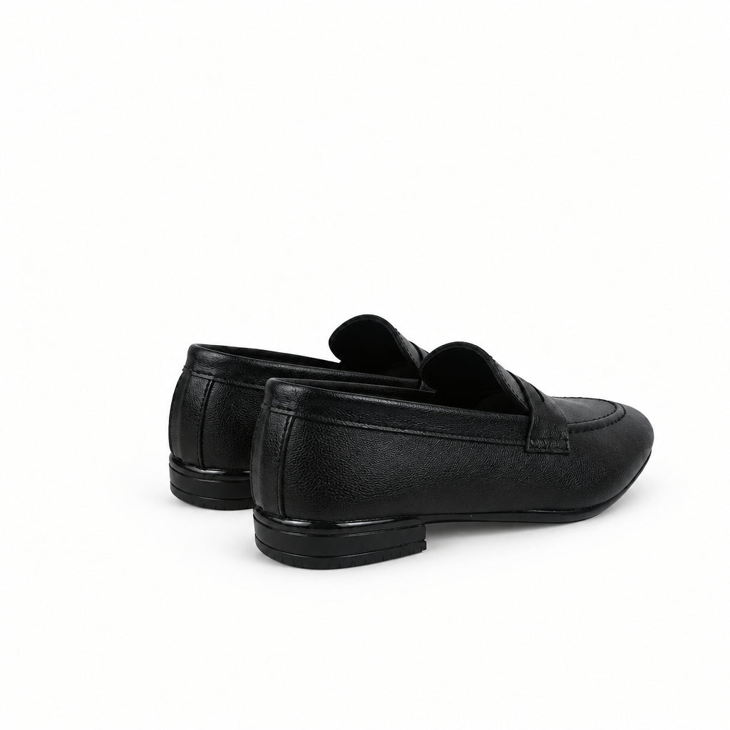 A pair of black leather penny loafers shown from a side-rear angle against a wrinkled white studio backdrop.