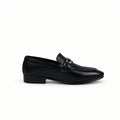 A single black leather loafer with a pointed toe and a small gold-tone horsebit detail on the strap, shown in profile against a white studio backdrop.