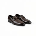 A pair of men's dark brown leather loafers with a glossy finish, featuring a decorative chain strap across the vamp, displayed on a white studio background.