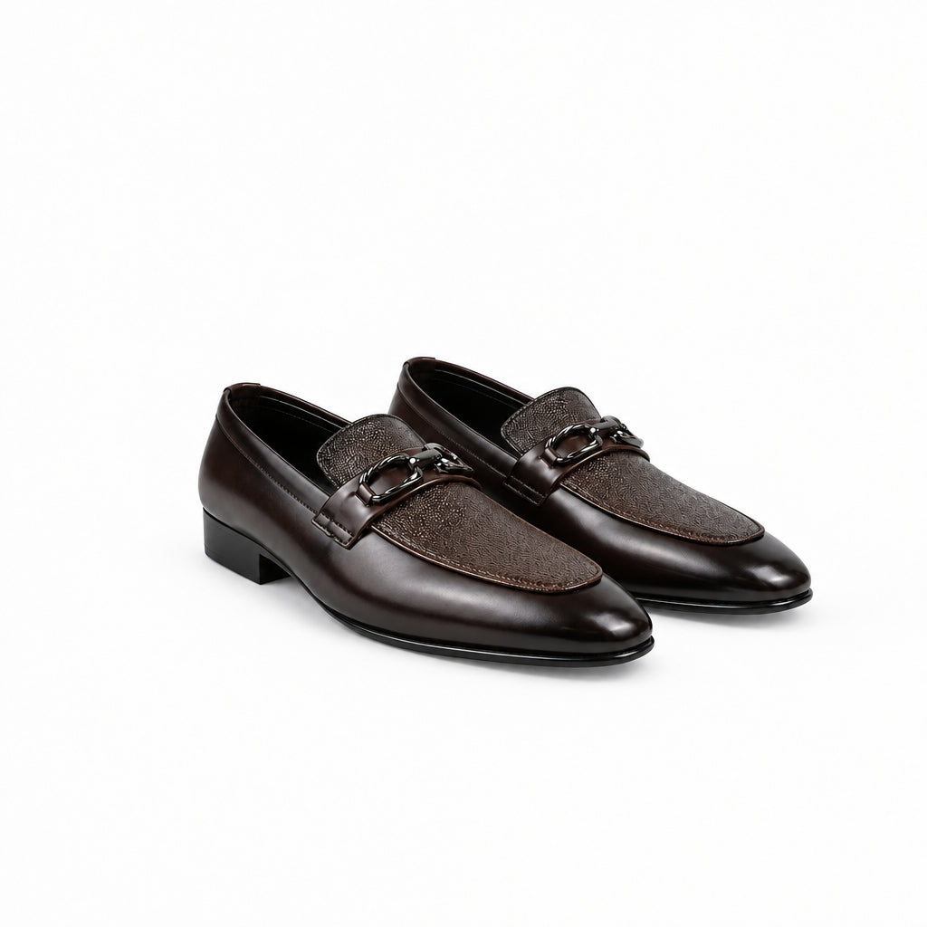 A pair of men's dark brown leather loafers with a glossy finish, featuring a decorative chain strap across the vamp, displayed on a white studio background.