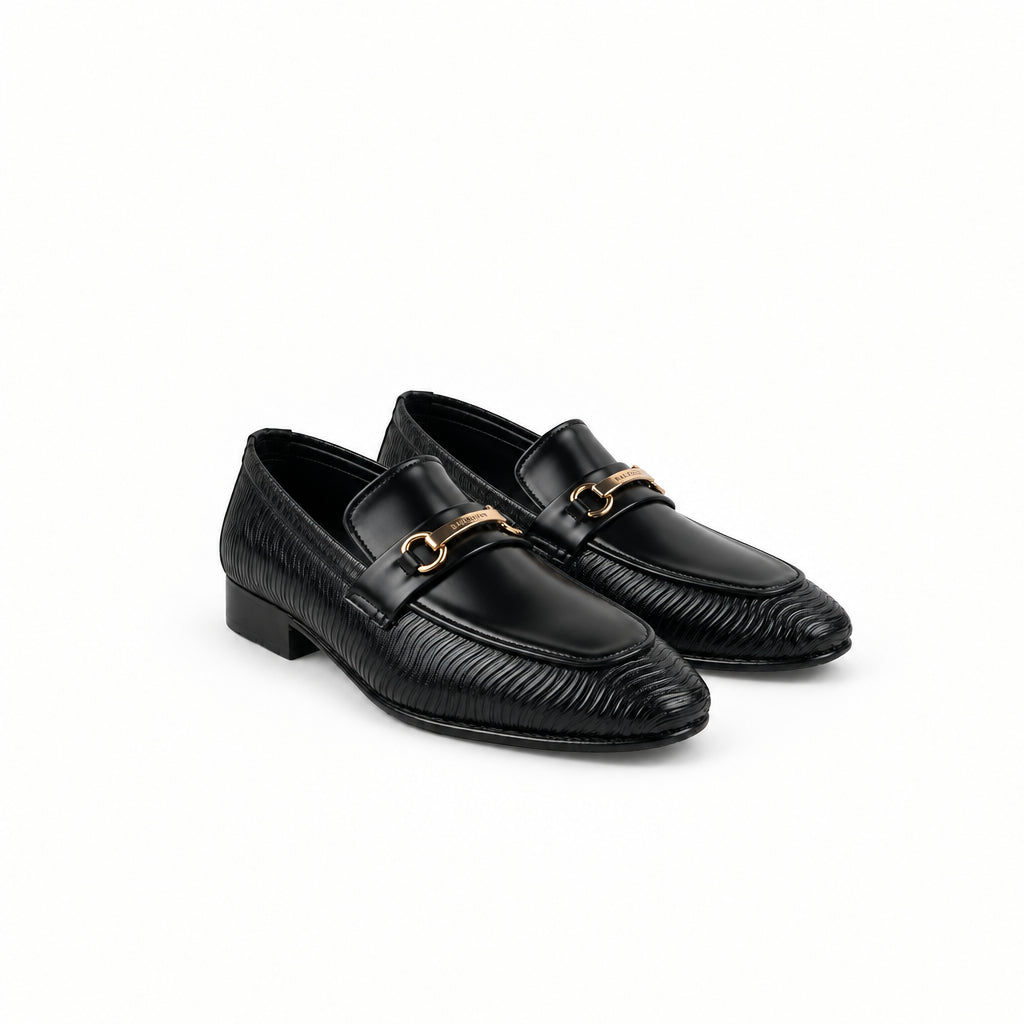 A pair of black leather loafers with a textured chevron pattern and a gold-tone horsebit detail across the vamp, displayed on a white fabric backdrop.