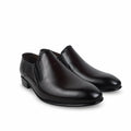 A pair of men's dark brown leather slip-on loafers with low block heels, displayed on a light gray surface with a crumpled white tissue in the background.