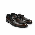 A pair of dark brown leather penny loafers with a textured pebbled finish, a decorative leather strap across the vamp, and low black stacked heels, shown on a plain white background.