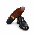 A pair of dark brown double monk leather shoes, with one shoe turned upside down to show the brown suede insole and gold heel accent, set against a white background with a blue and white box partially visible on the right.