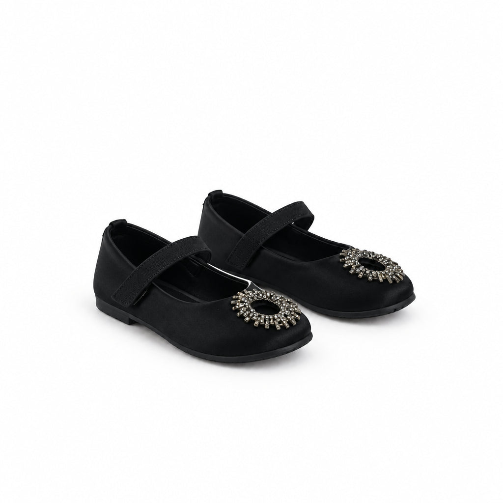 A pair of black Mary Jane style shoes with silver rhinestone embellishments on the toes, photographed on a white studio backdrop.