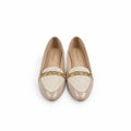 A pair of beige patent leather loafers with cream woven inserts and a gold chain detail across the vamp, photographed on a light gray surface.