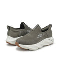 A pair of Skechers slip-on sneakers in a muted gray color, featuring a textured knit upper, a white sculpted midsole, and a brown outsole, shown against a plain light gray background.