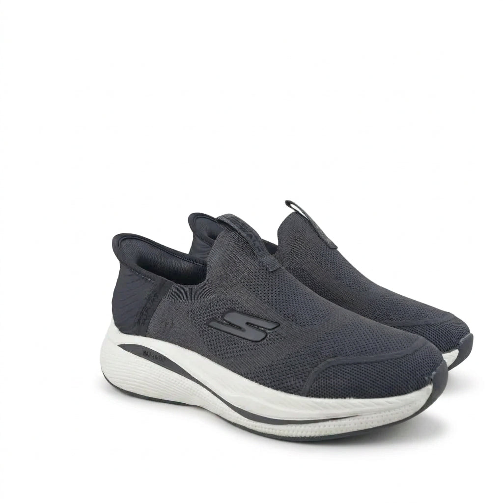 A pair of dark gray slip-on sneakers with a thick white and gray sole, displayed on a clean white background.