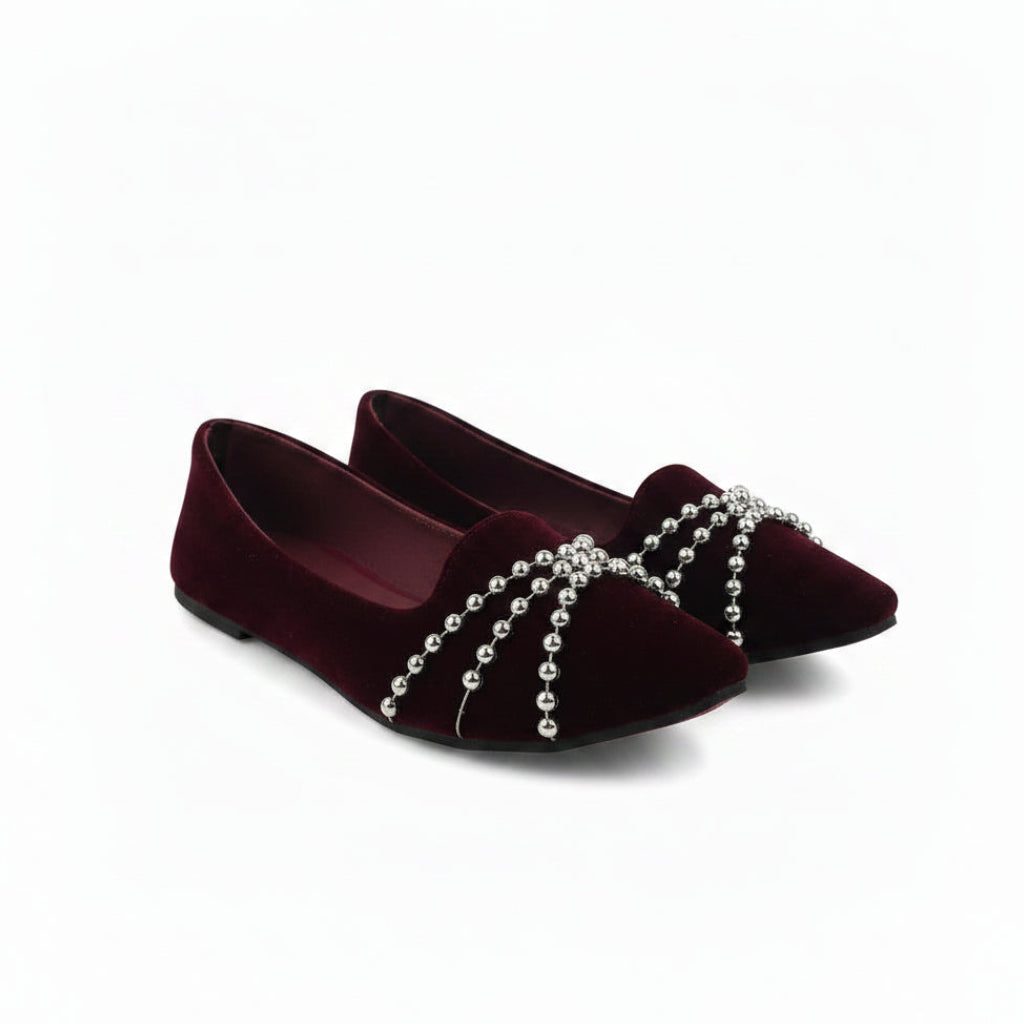 A pair of deep burgundy velvet flat shoes with silver beaded chains draped across the toe area, shown on a plain white background.