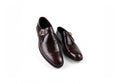 A pair of dark brown  men's dress shoes with a single strap and gold buckle detail, displayed on a clean white background.
