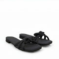 A pair of black slide sandals with wide crisscross straps and a bow detail on the toe, set against a plain white background.