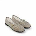 A pair of women's flat shoes in a light beige color, featuring a fishnet mesh upper with a grid pattern, double crossover straps with gold-tone buckle details, and a low black heel.