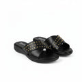 A pair of black slide sandals with gold-tone metal studs arranged in a crisscross pattern across the straps, shown on a plain white background.