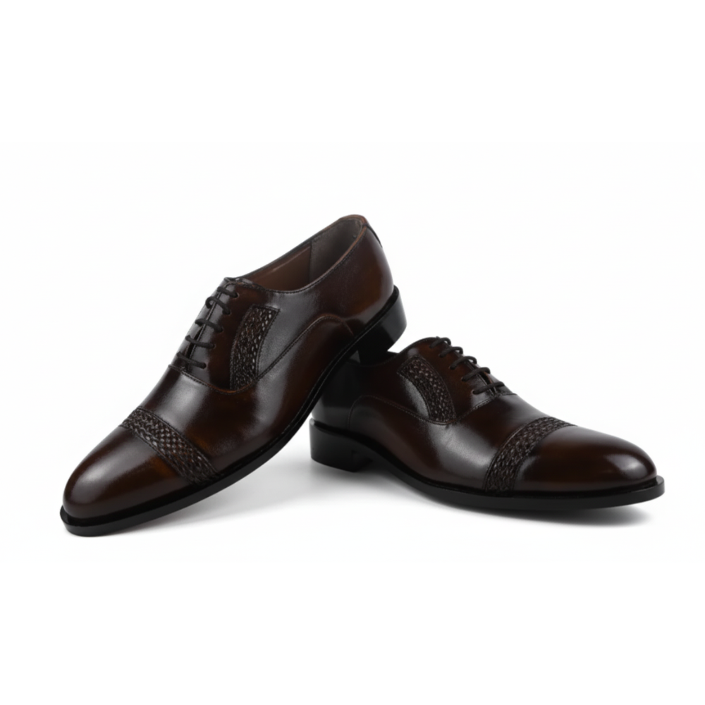 Pair of black dress shoes with woven details on a white background