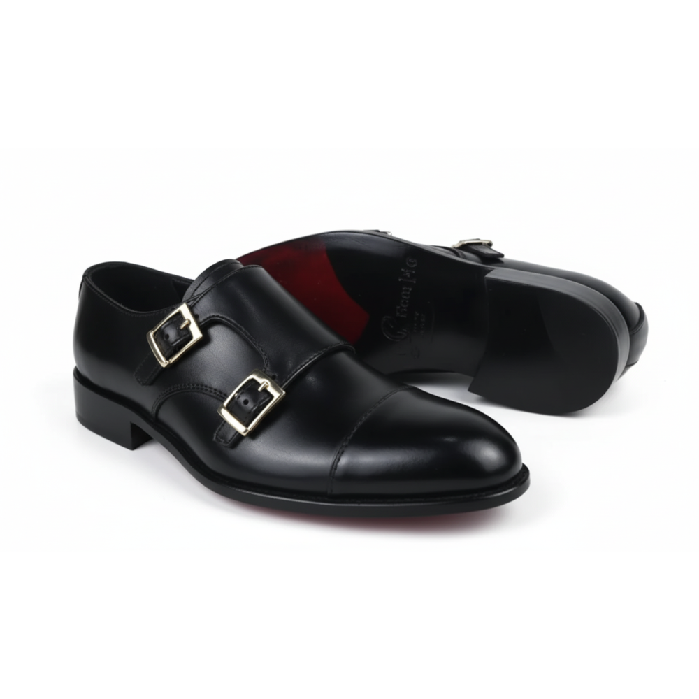 Black leather shoes with gold buckles on a white background