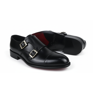 Black leather shoes with gold buckles on a white background